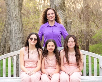women in a purple shirt with three girls all wearing pink