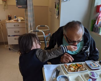 Zafira's  late father in the hospital, her young son feeds him