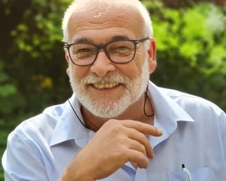 Patrick Beiner with a beard and glasses sitting in a chair