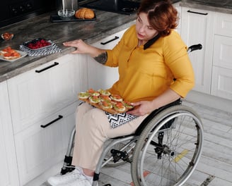 a woman in a wheelchair in her kitchen with a platter of food