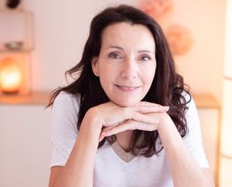 a woman sitting on a chair with her hands on her chin