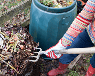 a woman turning over the compost pile
