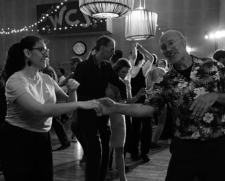 a woman in a floral shirt dancing with a man in a suit