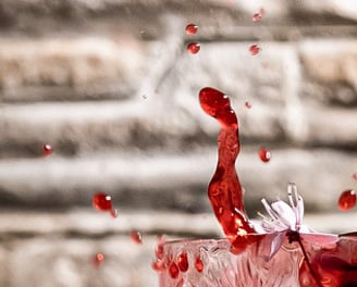 Schizzo rosso da un cocktail in cristallo con fiore di ciliegio – fotografia emozionale e dinamica a