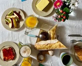 Brunch gourmand avec viennoiseries, fruits frais et fleurs, servi dans une location de charme