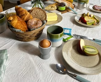 Petit-déjeuner gourmand avec viennoiseries, fruits frais et fleurs, servi dans une location de charme