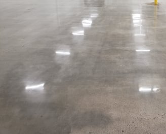 polished concrete in the inside of a building with lights reflecting from it
