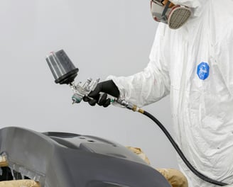 a man in a white suit and a white coat painting a car white at fix collision center