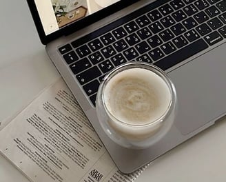 a laptop computer sitting on a table with a cup of coffee