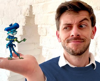 Young handsome gay male artist wearing a blue jumper holds one of his fantasy art figures.