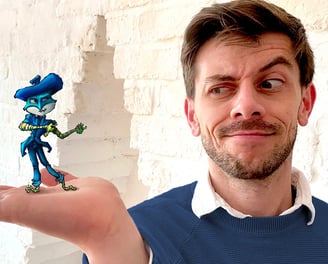 Young handsome gay male artist wearing a blue jumper holds one of his fantasy art figures.