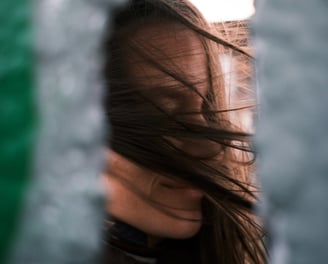 a woman with long hair and a black jacket. wind is blowing in the hair.