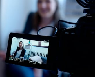 Interior shot of smiling woman being video recorded