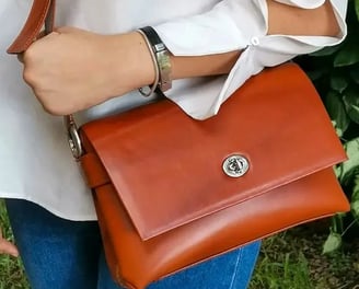 a woman in a white shirt and jeans jeans and a brown purse