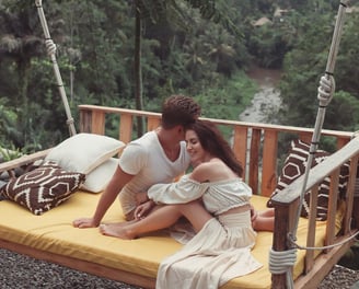 a man and woman sitting on a swing - swing