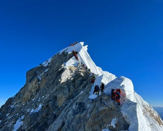Climbers on snowy peak – Mountaineers ascending a snow-covered mountain ridge under a clear blue sky