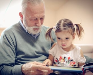 an elderly gentleman reading to a young girl