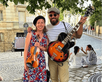 a man and woman standing in front of a guitar