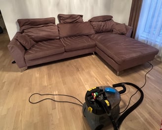 sofa su šalia stovinčia gilaus valymo chemijos mašina karcher, demonstruojanti švarią sofą