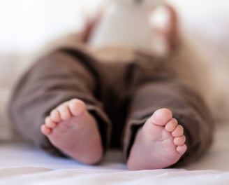 Baby Füße auf dem Bett mit Spielzeug-Hase