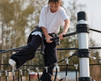 Fille grimpant sur une structure Kenguru Pro Kids Active Play en extérieur.