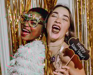 femmes souriantes portant des accessoires festifs dans une cabine photobooth, célébrant le Nouvel An