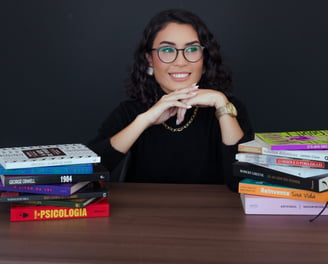 a woman sitting at a table with books and a book