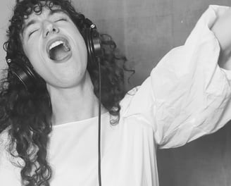 photo en noir et  blanc de aude fy en train de chanter avec casque sur les oreilles
