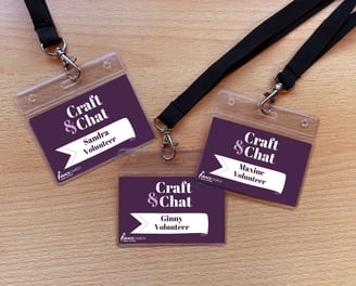Three "Craft & Chat" volunteer lanyards with a deep purple design, featuring white name tags.