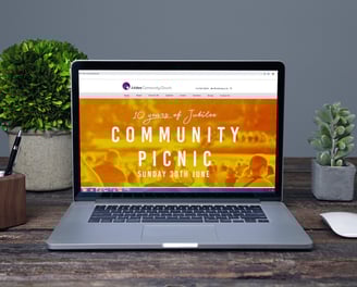 Laptop screen displaying Jubilee Community Church’s website with a Community Picnic event banner.