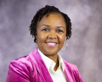 headshot of East Texas Custom Home builder Tracy Dews in magenta blazer and white shirt