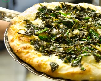 a pizza with spinach and cheese on a pan