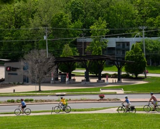People biking on a sidewalk near a road
