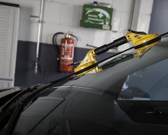 a car with a yellow handlebarb in the back ground at fix collision center fixing its broken glass