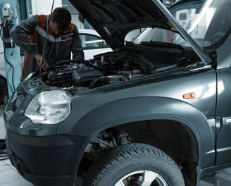 a man working on a car in a garage at fix collision center