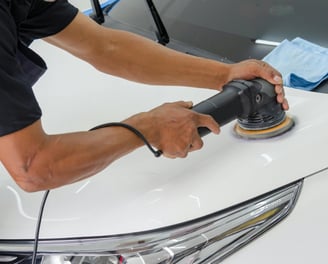 a man is buffing a white car at fix collision center