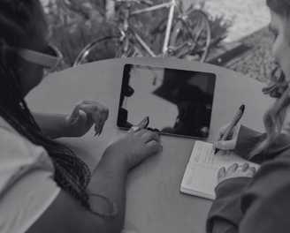 foto preto e branca de mulheres empreendedoras conversando com um tablet na mesa