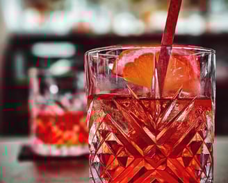 a glass of red wine with a strawberries and oranges