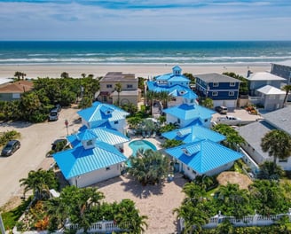 a beachfront home with blue roofing and blue roofing