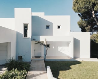 a white house with a white wall and a tree