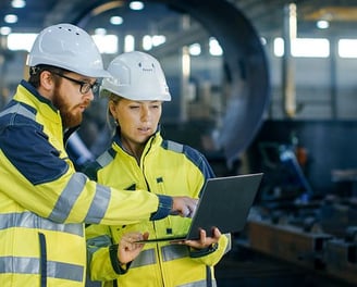 two people in safety gear standing in a factory