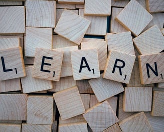 Wooden letter tiles spelling 'LEARN' on a scattered block background, symbolizing language learning 