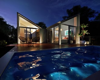 Woodland prefab guesthouse with timber interiors, large windows, outdoor pool, sustainable retreat