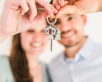 a man and woman holding keys to their house