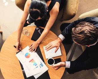 a man and woman sitting at a table with papers and papers