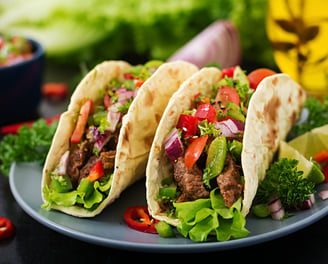 Two halal tacos filled with seasoned meat and toppings, without sauces.