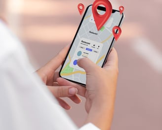 Mano sosteniendo un teléfono móvil con un mapa y varios pines de ubicación resaltando negocios local