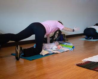 Mother in Spinal Balance yoga pose with Infant under her.