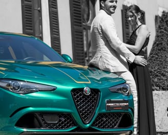 "Coppia elegante accanto a un'Alfa Romeo verde in strada di città, fotografia emozionale gaudife