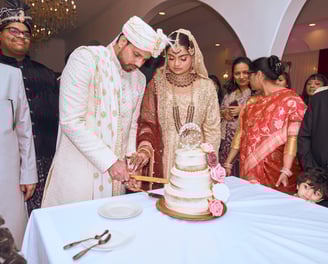 a man and woman are cutting their wedding cake